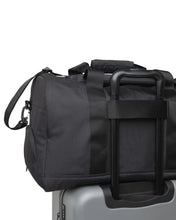 Load image into Gallery viewer, Back panel view of the duffle bag attached to the telescopic handle of a suitcase.