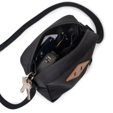 Load image into Gallery viewer, Top interior view of a black crossbody bag with keys and accessories organized inside.
