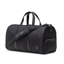 Load image into Gallery viewer, Angled front view of the black duffle bag with the shoulder strap across it.