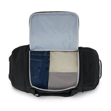 Load image into Gallery viewer, The black duffle bag with the main compartment unzipped. A set of clothes is folded and organized inside.