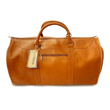 Load image into Gallery viewer, Front view of the tan leather garment duffle bag. It has a Daytrekr tag attached to the grip handle.
