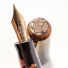 Load image into Gallery viewer, Close up to the fountain pen's nib and the top of the cap. There are are flowers painted at the top of the cap and on the pen's grip section.