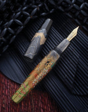 Load image into Gallery viewer, The Fountain Pen with the cap set to the side. Both items are placed on a set of black and brown layered items.