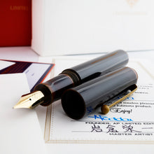 Load image into Gallery viewer, Angled view of the fountain pen with the cap set to the side, on top of the included documents. The pen's clip is a caramel-yellow. The body is a dark dark coffee-brown with the edges being a slight yellow.
