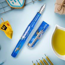 Load image into Gallery viewer, View of the pen with the cap set next to it on a light blue background. It is surrounded by different accessories themed by the Hanukkah celebration (not included).