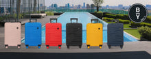 Load image into Gallery viewer, 6 Suitcases by Bric's lined up on a background with a pool and greenery. The colors are pink, blue, red, black, yellow, and navy blue.