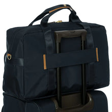 Load image into Gallery viewer, Back view of the duffle placed on top of a suitcase. Set on a white background. The suitcase's telescopic handle is pulled through the duffle's horizontal strap to keep it in place.