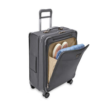 Load image into Gallery viewer, Front angled view of the suitcase. The front panel compartment is unzipped and holds a jacket and a pair of shoes.