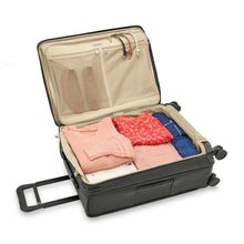 Load image into Gallery viewer, Interior view of the suitcase shown packed with folded clothes.