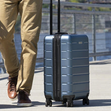 Load image into Gallery viewer, Angled view of the suitcase being rolled on a sidewalk.