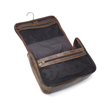 Load image into Gallery viewer, DayTrekr Hanging Toiletry Kit - Brown Distressed Leather
Angled Interior View showing the hanging toiletry kit fully unzipped. Inside Antique brass hanger hook and two inside zippered mesh pockets.
Dimensions: 11"(w) x 9"(h) x 4"(d)
