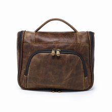 Load image into Gallery viewer, DayTrekr Hanging Toiletry Kit - Brown Distressed Leather
Front Panel View showing U-Shaped Zippered Opening into front panel organizer pocket. Matching Leather top handle grip.
Dimensions: 11"(w) x 9"(h) x 4"(d)