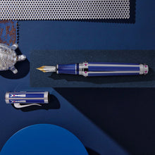Load image into Gallery viewer, A series of blue and white decorations placed on the background surround the Fountain Pen. It is placed with the cap next to it.