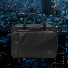 Load image into Gallery viewer, Front view of the black Gibson messenger bag, with a background of a birds-eye view of a city