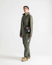 Load image into Gallery viewer, A young woman dressed in green, carrying the black cross body bag.