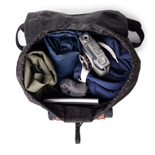 Load image into Gallery viewer, Top view of the opened backpack filled with clothing, a notebook, and a camera.
