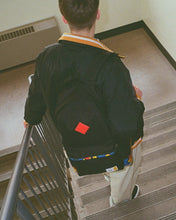 Load image into Gallery viewer, A young man carrying the black Lego backpack while going down a flight of stairs.
