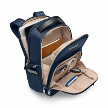 Load image into Gallery viewer, Angled view of the navy blue backpack with all the compartments opened. A laptop, tablet, notebook, passport, notebook, cable, pen, and keys on a key sling are organized in different pockets.