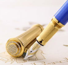 Load image into Gallery viewer, Close up to the Fountain Pen nib and cap. The cap is angled to show the pave on top. 65 VV Diamonds decorate the cap. The Nib is decorated in both yellow and white gold with the engraving of the Michel Perchin Elephant, and the M for the Medium Nib point.