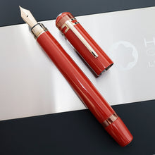 Load image into Gallery viewer, The fountain pen with the cap next to it, set on top of the presentation box.