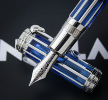 Load image into Gallery viewer, A close-up of the fountain pen nib, shown with its matching blue and silver cap on a dark background.