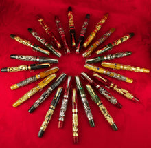 Load image into Gallery viewer, Montegrappa Chinese Zodiac fountain pen collection displayed in a circular layout on red fabric, featuring luxury handcrafted pens with gold and silver overlays representing the 12 zodiac animals.