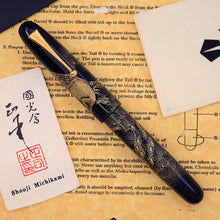 Load image into Gallery viewer, Fountain pen with intricate design on a lettered background with artist card on the side.