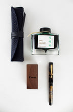 Load image into Gallery viewer, The Fukurokuju fountain pen arranged with the green ink bottle, small wooden compartment, and pen case on a white background.
