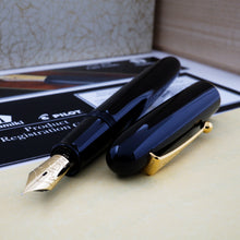 Load image into Gallery viewer, The black fountain pen with gold trims arranged with the cap to the side with its included documents and boxes.