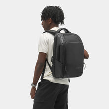 Load image into Gallery viewer, A young man carrying the black backpack.