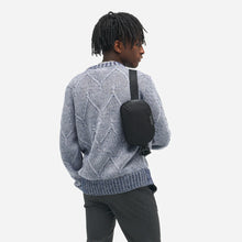Load image into Gallery viewer, Back view of a young man carrying the black sling bag.