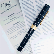 Load image into Gallery viewer, Side view of the fountain pen with the cap on, laid on the included documents.