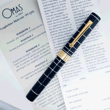 Load image into Gallery viewer, Front view of the fountain pen with the cap on, laid on the included documents.