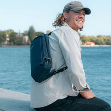 Load image into Gallery viewer, Man with a sling bag sitting by a lake