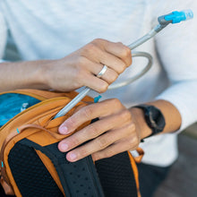 Load image into Gallery viewer, A person holding the bag and pulling a water straw from an opening on the top panel.