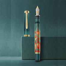 Load image into Gallery viewer, The fountain pen arranged on a green background with the cap set next to it.