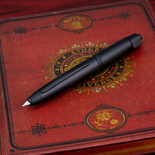Load image into Gallery viewer, The matte black Vanishing Point LS is set on top of a red book cover decorated with black and yellow-gold accents.