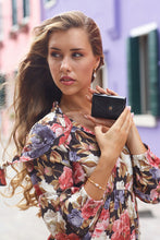 Load image into Gallery viewer, A young woman holding a black wallet in an urban setting.