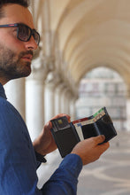 Load image into Gallery viewer, A young man pulling a credit card from his wallet.