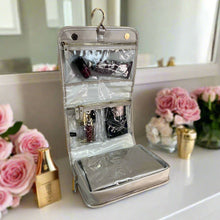 Load image into Gallery viewer, The extended toiletry case with cosmetics on a vanity table with flowers and perfume bottles.