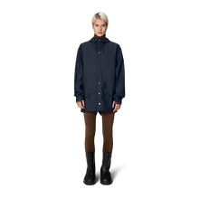 Load image into Gallery viewer, A young woman wearing the navy blue rain jacket and black rain boots.