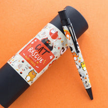 Load image into Gallery viewer, The ballpoint pen leaning on the matching gift tube on an orange background.