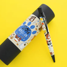 Load image into Gallery viewer, The Dog Rescue ballpoint pen leaning on the matching gift tube on a yellow background.
