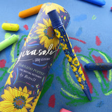 Load image into Gallery viewer, The pen leaning on its matching gift tube. Set on a blue background with sketches.