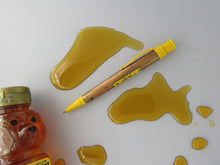 Load image into Gallery viewer, Side view of the pen and bear-shaped bottle with honey spilled around it.
