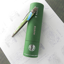 Load image into Gallery viewer, The pen sits sideways on top of the green presentation tub with a white background.