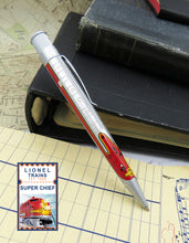 Load image into Gallery viewer, Side view of the rollerball pen leaning on some folders.