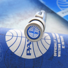 Load image into Gallery viewer, The pen top resting on its blue presentation tube. The focus is on the disk, which is showing the PAN AM logo.