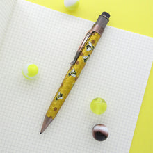 Load image into Gallery viewer, Side view of the mechanical pencil placed on a grid paper notebook and some marbles.