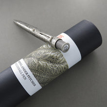 Load image into Gallery viewer, The rollerball pen leaning on the gift tube. The top disk has The Met's logo printed on it.